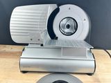 a close up of a meat slicer on a cutting board