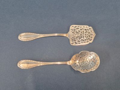 deux cuillères en argent ornées de motifs élaborés, posées sur un fond bleu