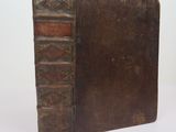 un vieux livre à la couverture marron posé sur une table blanche