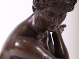 statue of a woman sitting on a rock with her hand on her chin