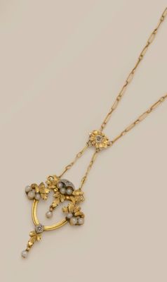 a close up of a gold necklace with pearls and flowers