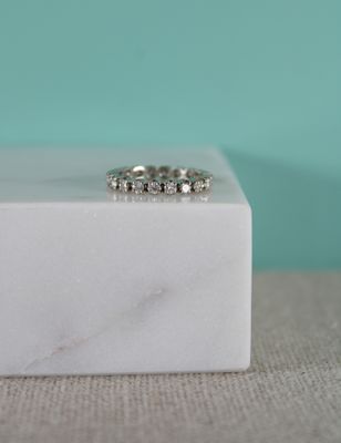 un gros plan d'une bague posée sur un bloc de marbre blanc