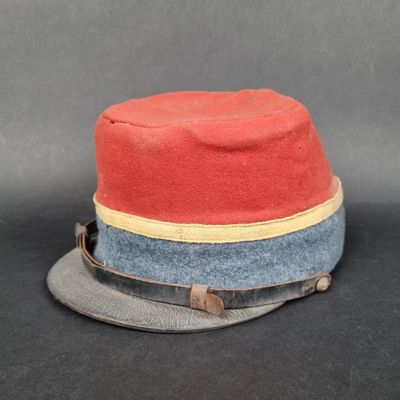 un chapeau rouge orné d'un ruban bleu et un chapeau gris orné d'un ruban jaune