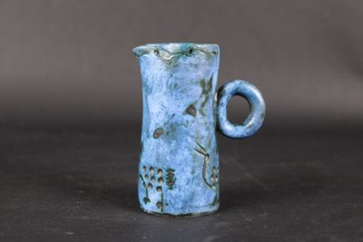 a small blue vase with a handle on a table