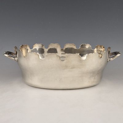 silver plated bowl with handles and handles on a white surface