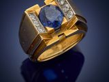 a close up of a gold ring with a blue sapphire and diamonds