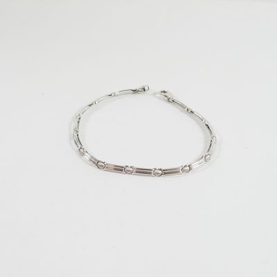 un bracelet en argent posé sur une table blanche, sur fond blanc