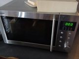 a microwave oven sitting on a counter with a box of tomatoes