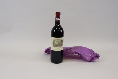 une bouteille de vin posée sur une table à côté d'un sac violet
