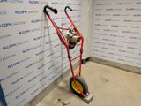 a red hand truck with a yellow wheel in front of a wall