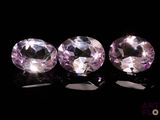 three pink sapphires sitting on top of a black surface