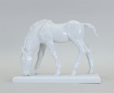 une statue blanche représentant un cheval en train de brouter, posée sur une surface blanche