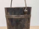 an old metal bucket with a handle sitting on a wooden table