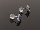 a pair of sapphire and diamond stud earrings on a reflective surface