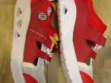 pair of red and white shoes on a wooden floor next to a box of harry potter books