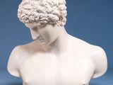 a white marble bust of a man with curly hair on a blue background