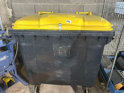 une poubelle jaune et noire posée dans un garage