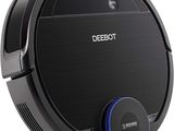 un aspirateur robot noir posé sur une surface blanche, muni d'un bouton bleu
