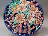 an image of a decorative plate with flowers and leaves on it