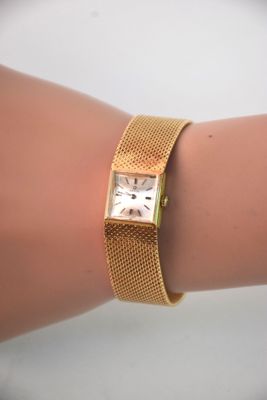 le poignet d'une femme auquel est attachée une montre en or