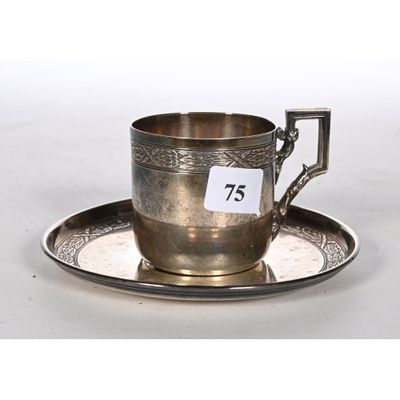 a silver cup and saucer on a saucer with a number 75 on it