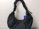 the black bag is sitting on a white surface with a blue tag attached to it