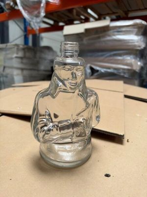 une bouteille en verre ornée d'une statuette, posée sur une table