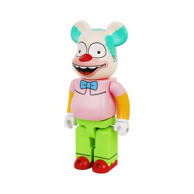 Ce jouet est en plastique ; il porte une chemise rose et un pantalon vert.