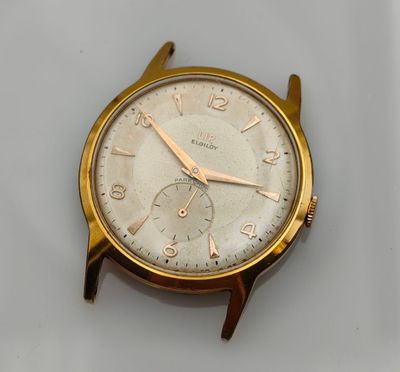 gros plan d'une montre en or sur une surface blanche