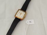 a close up of a watch on a white surface with a tag