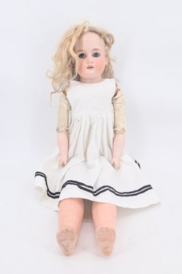 une vieille poupée aux cheveux blonds, assise sur une surface blanche