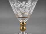 a glass goblet with a gold rim and floral design