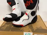 a pair of white and black motorcycle boots on a cardboard box