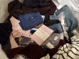 a pile of clothes in a plastic bag on a bed