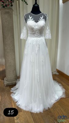 une robe de mariée posée sur un mannequin devant un vase de fleurs