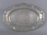 a silver plate with a scalloped edge on a gray surface