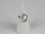 bague en argent avec une pierre blanche sur un cône blanc, sur fond blanc