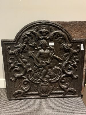an old cast iron fireplace screen with a clock on it