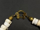 a close up of a necklace with white beads and gold accents