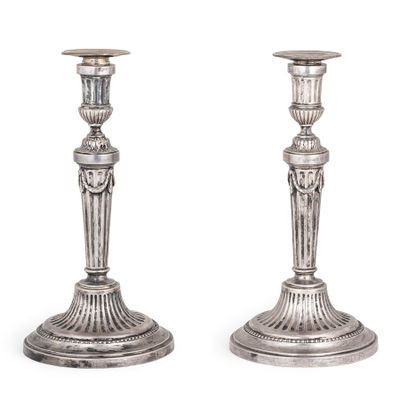 une paire de bougeoirs anciens en argent posés sur des socles, sur fond blanc