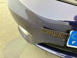 a close up of a blue car with a ruler on the front of it