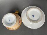 pair of porcelain cups and saucers with blue flowers on them