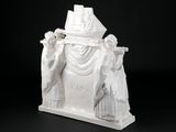 sculpture représentant un homme blanc coiffé d'un chapeau, située au sommet d'un immeuble
