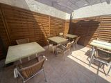 tables and chairs on a patio with an umbrella over them