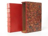 un vieux livre à la couverture rouge, ouvert sur une surface blanche