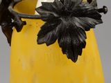 a yellow vase with a black flower on it