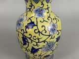 un vase jaune orné de fleurs bleues et blanches