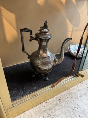a silver tea pot on display in a glass case