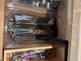 a lot of silverware in plastic containers on a shelf
