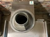 a metal vent in the middle of a brick wall